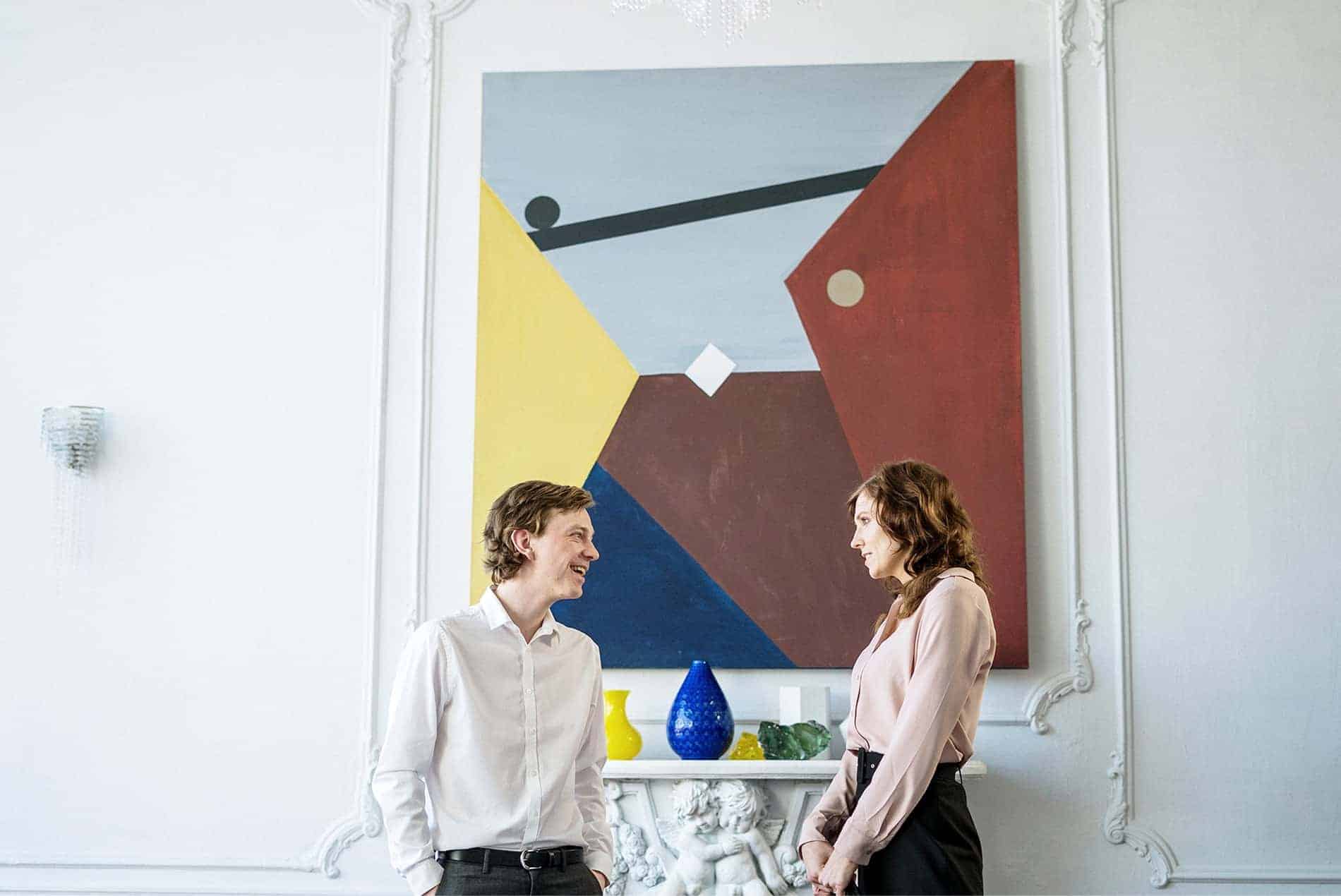 Modern art gallery with two women engaging in conversation.